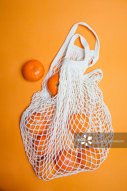橘色背景下，网兜里的橘子图片素材
