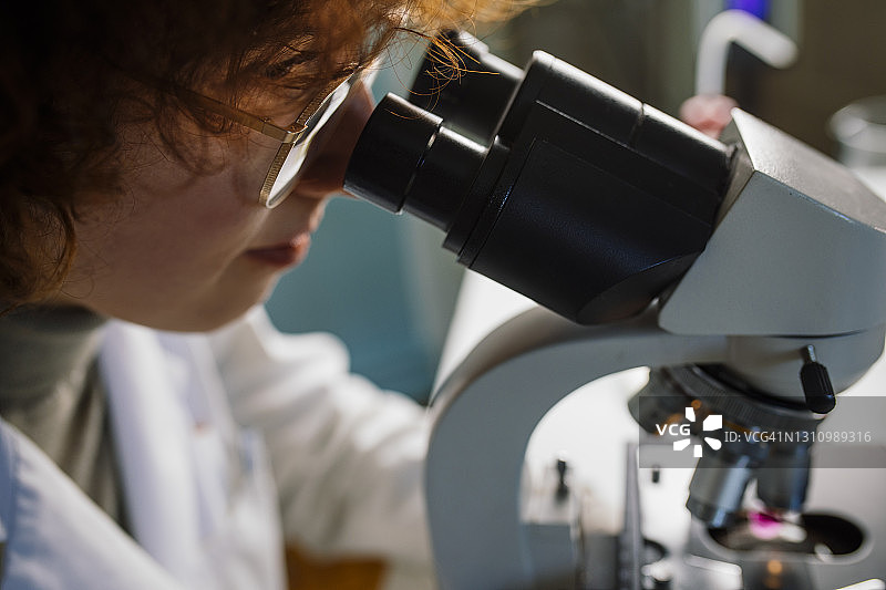 在医院实验室用显微镜观察的年轻医学研究员图片素材