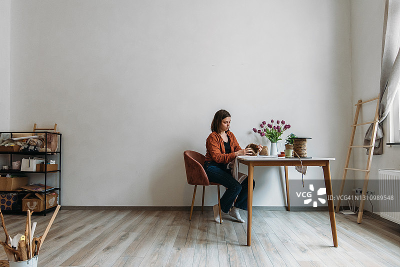 年轻女子在工作室的桌旁编织图片素材