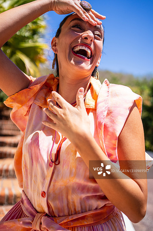 穿着色彩鲜艳印花连衣裙摆姿势欢笑的女人图片素材