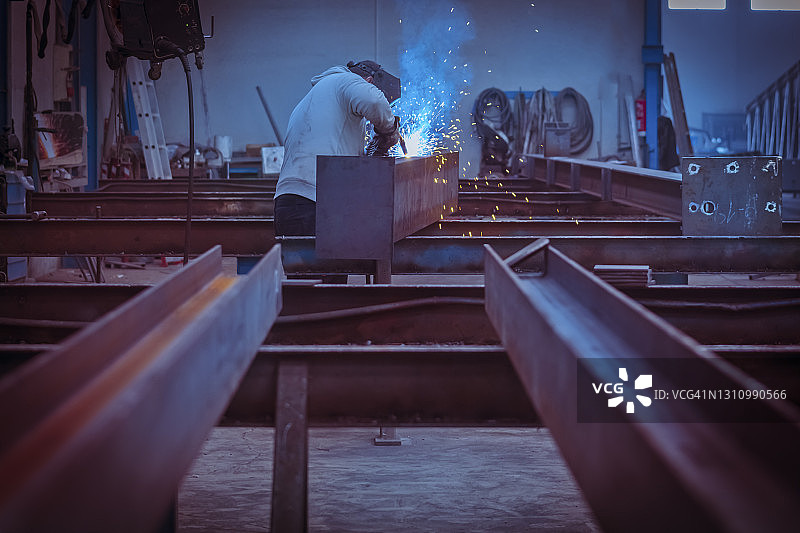 戴防护面罩焊接工业钢梁的男人图片素材