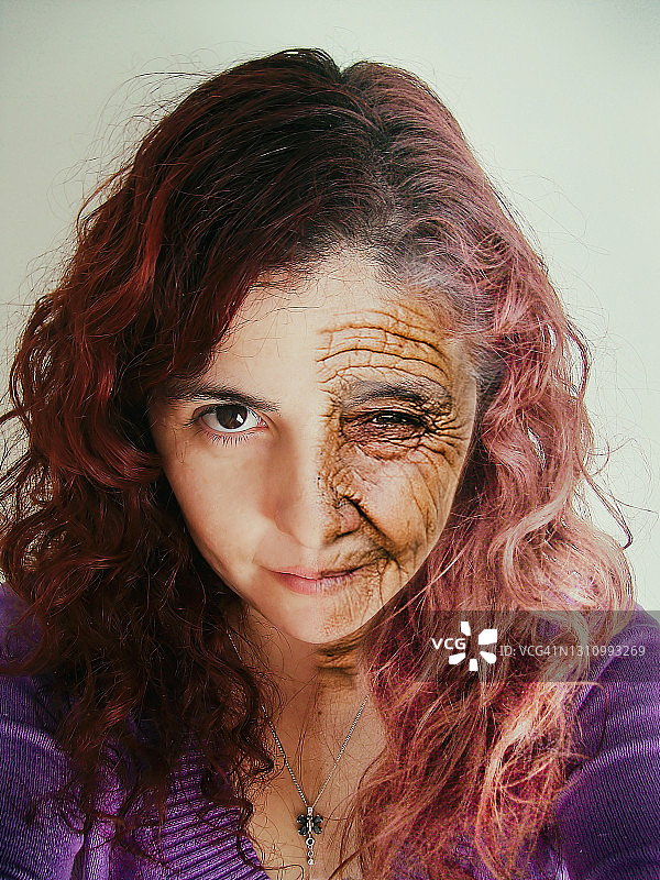 超现实画像。半个年轻女人和半个老女人看着相机。图片素材