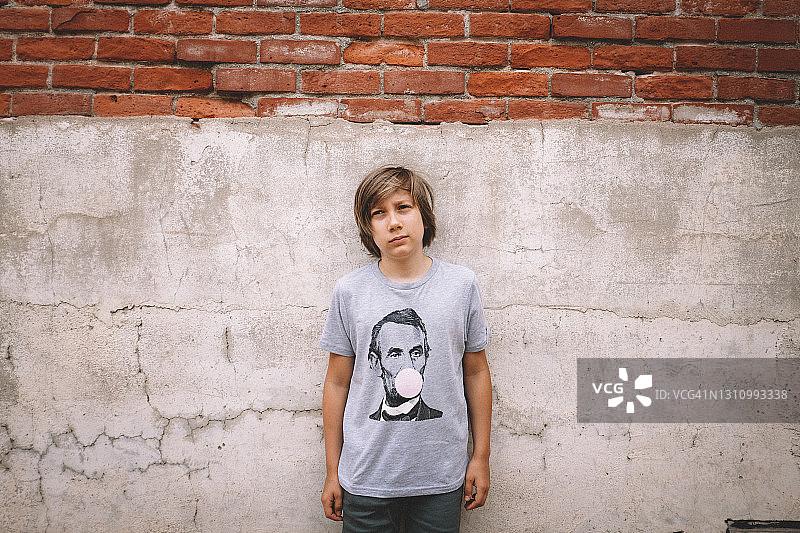 男孩靠在绘有亚伯拉罕·林肯和泡泡糖的砖墙上图片素材