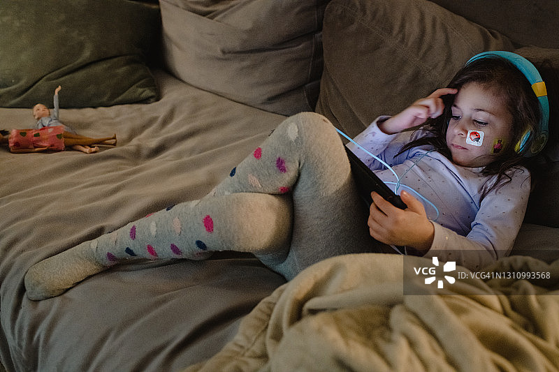 年轻女孩戴着耳机看平板电脑图片素材