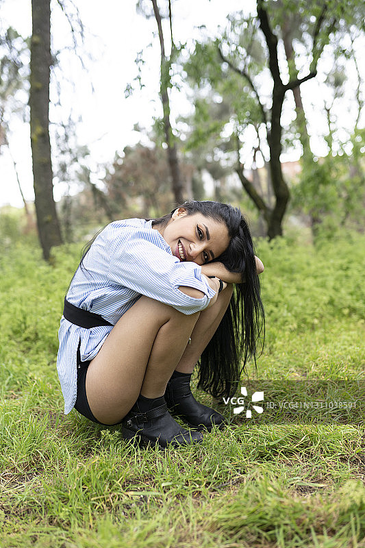 美丽长发拉丁美洲女人坐在森林中图片素材