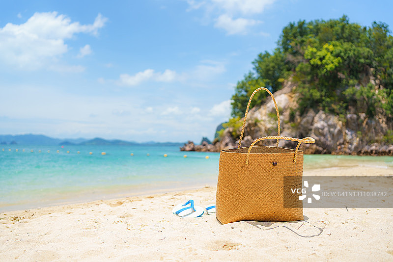 夏季海滩上的篮子和拖鞋，背景是美丽的海景和天空。图片素材