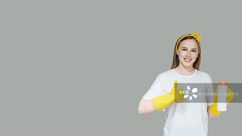 戴着橡胶手套的年轻家庭主妇拿着清洁剂，在做家务时做出积极的姿势图片素材