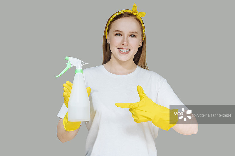 戴着黄色橡胶手套的年轻女孩，灰色影棚背景，清洁概念图片素材