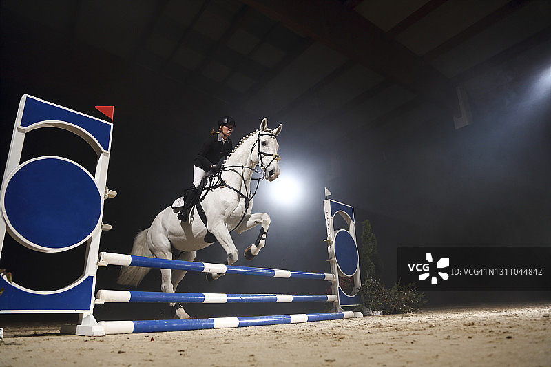 年轻女孩骑马跳过障碍图片素材