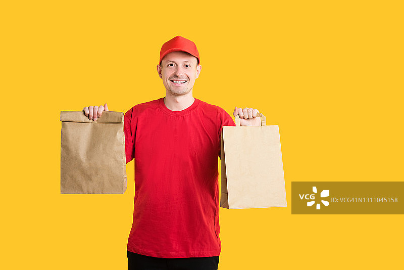 来自在线商店的外卖服务。红色制服的快递员在黄色背景上递送快餐订单。留白图片素材