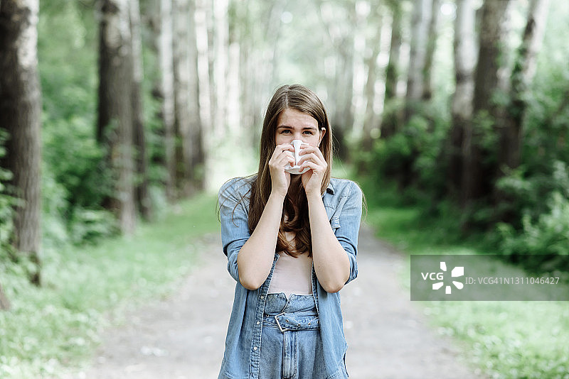 在公园里围着围巾，鼻子因过敏或疾病而流涕的年轻女人图片素材