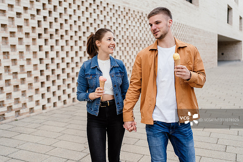 年轻情侣在城市中边走边吃冰淇淋图片素材