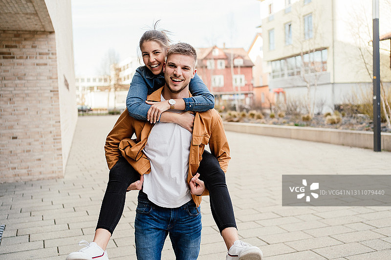 年轻夫妇在街头玩 piggyback 游戏图片素材