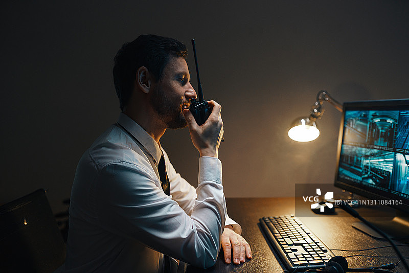 保安通过便携式无线电发射器观看视频监控安全系统图片素材