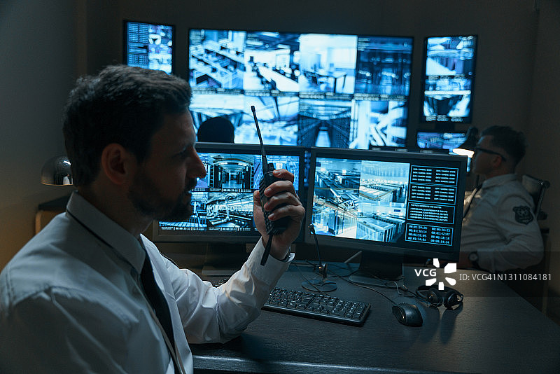 一名警卫打报告，另一名用对讲机与楼下警官通话图片素材