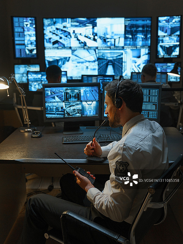 配备高科技跟踪系统的安保服务办公室，员工在各自的工作场所工作图片素材