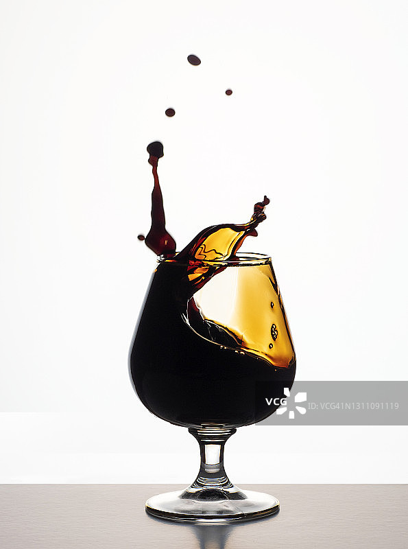 酒杯中飞溅的烈酒白色背景图片素材