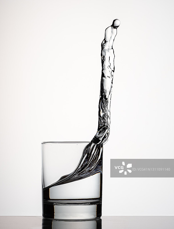 一杯水落在白色背景的桌子上图片素材