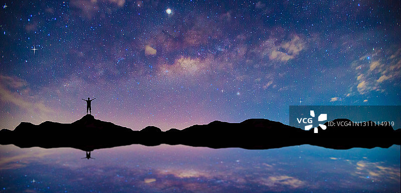 山顶旅行者剪影：蓝色星空银河背景图片素材