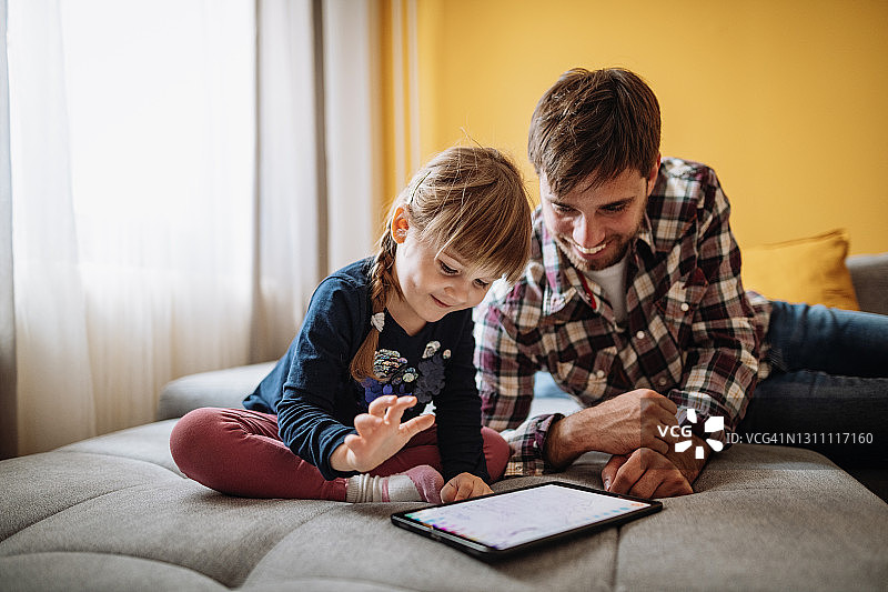 千禧一代父亲和女儿在平板电脑上玩在线游戏图片素材