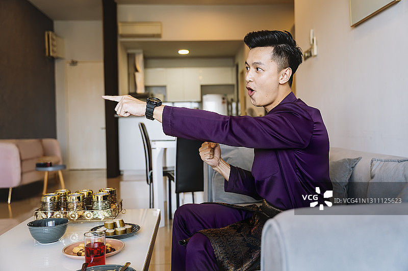 年轻男人穿马来传统服装看电视体育比赛图片素材