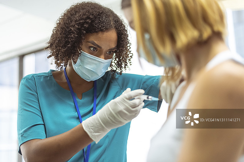 混血护士为病人注射新冠疫苗图片素材