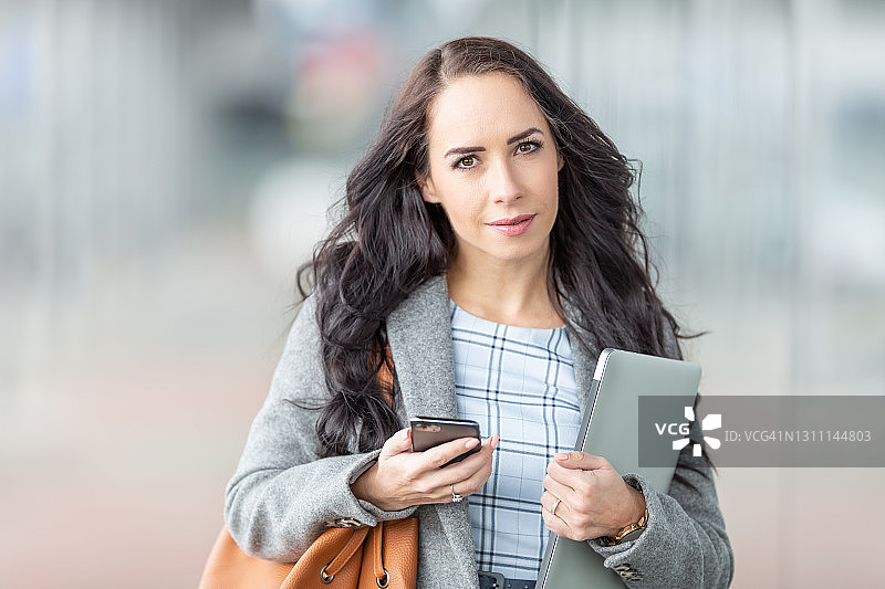 寒冷的早晨，女人手持最新科技产品去上班图片素材