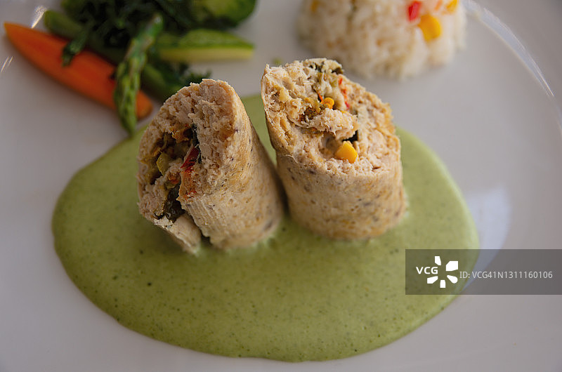 酿入西葫芦花、玉米和马苏里拉奶酪的鸡胸肉卷，配香菜酱、混合蔬菜和米饭图片素材