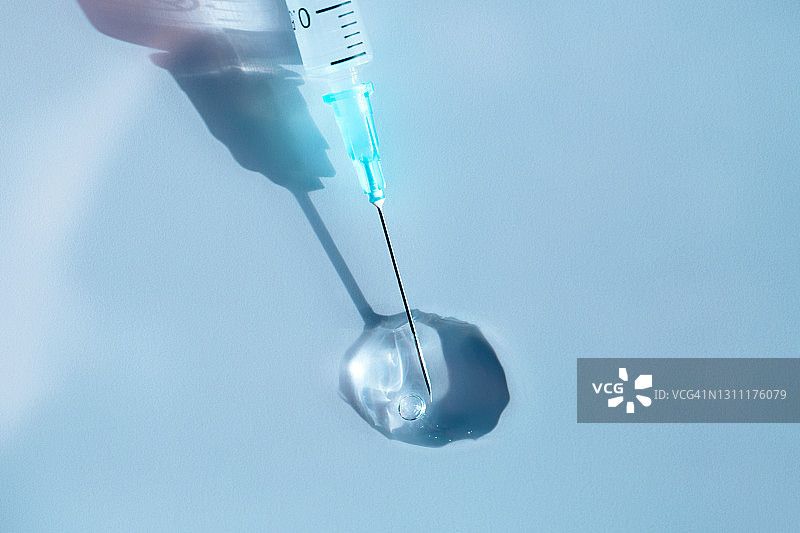 蓝色背景药液中带细针的无菌注射器特写图片素材