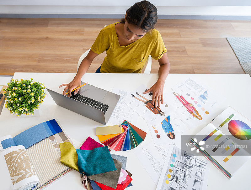 时装设计师在工作室绘制草图并使用笔记本电脑图片素材
