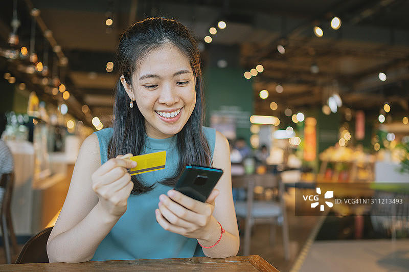 使用手机应用程序购买加密货币的快乐亚洲千禧一代女性图片素材