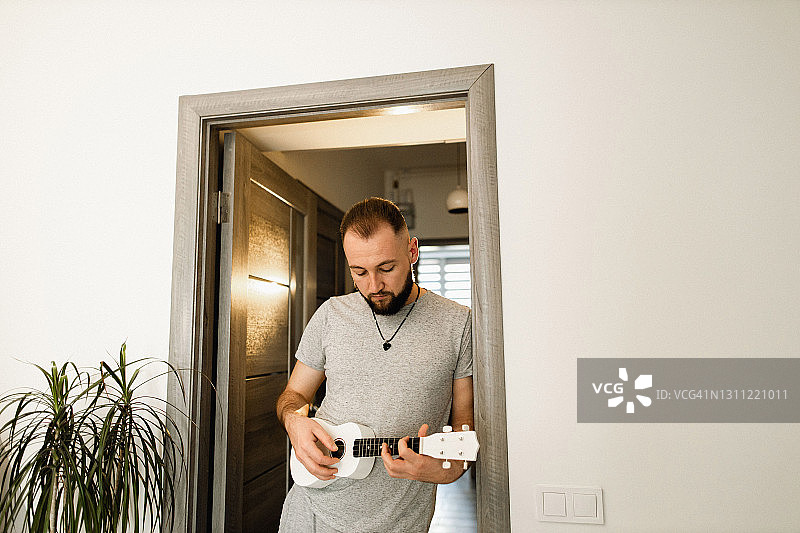 在门口弹奏尤克里里琴的年轻人图片素材