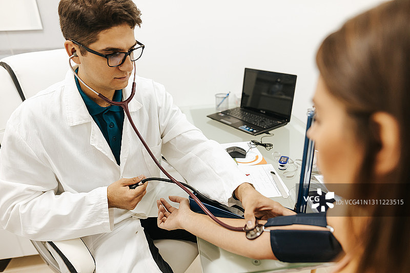 年轻女患者在医生办公室测量血压图片素材