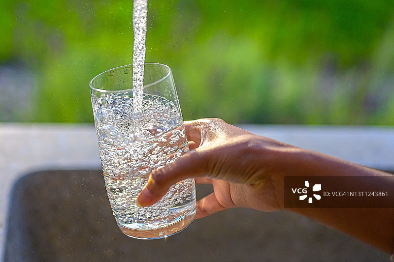 女人往玻璃杯里倒水图片素材