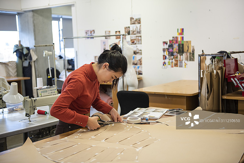 年轻的亚洲女性时装设计师在工作室工作图片素材