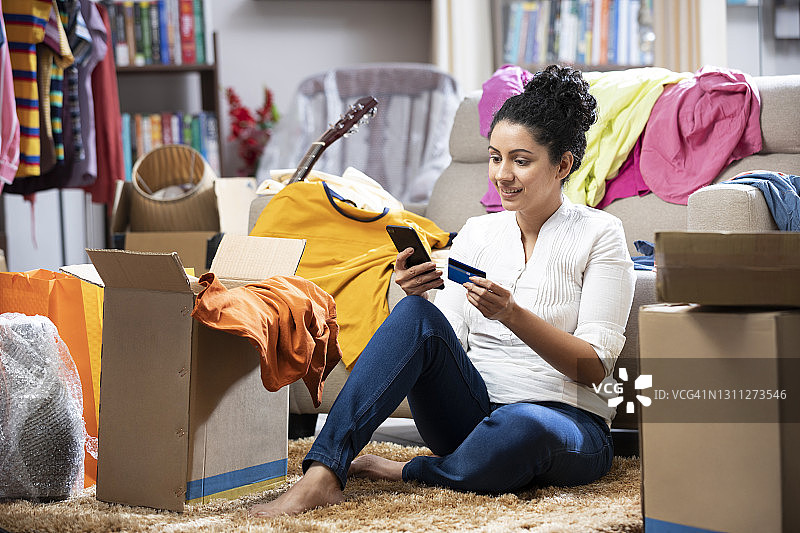 年轻女子在家用地板上的智能手机信用卡支付账单照片图片素材