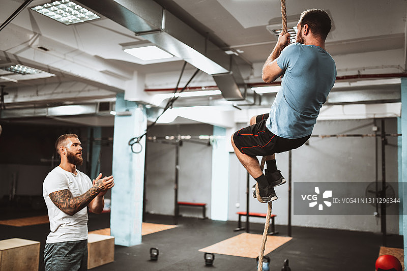 健身教练为男子成功完成攀绳训练鼓掌图片素材