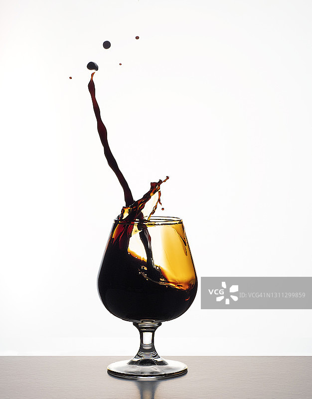 酒杯中飞溅的烈酒白色背景图片素材