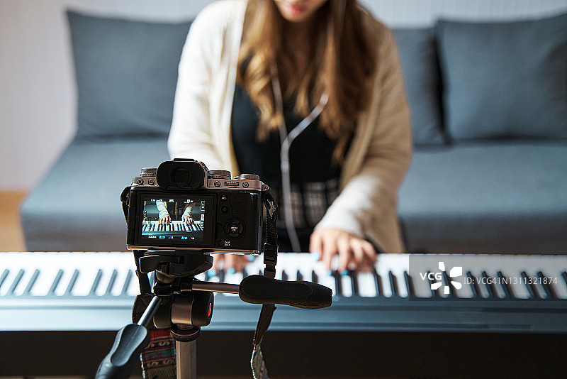 女人用专业相机录制自己弹钢琴图片素材