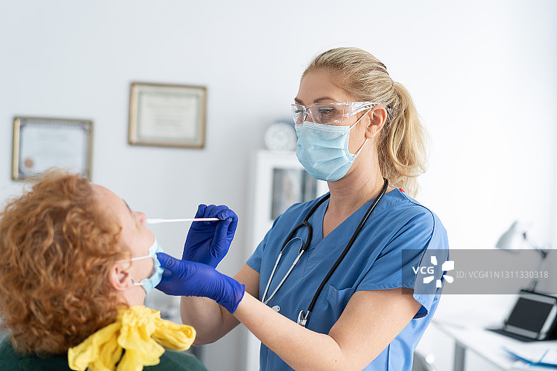 医生戴着防护口罩，从一名女性身上提取鼻拭子，以检测可能的新冠病毒感染图片素材