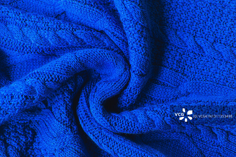 针织蓝色毛衣的纹理以漩涡状图案折叠，平铺风格，特写图片素材