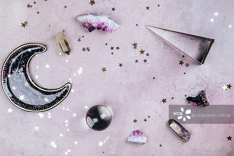 用于仪式的魔法水晶。深奥的套装，包含许多工具，形成一个框架，用于在混凝土灰色背景上复制空间，并带有银色和金色星星亮片。平铺风格图片素材