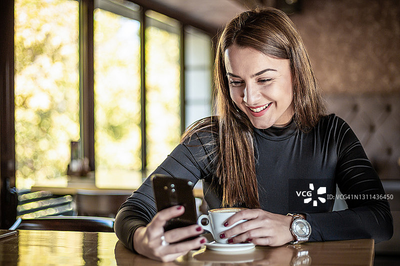 在自助餐厅使用智能手机的女人图片素材