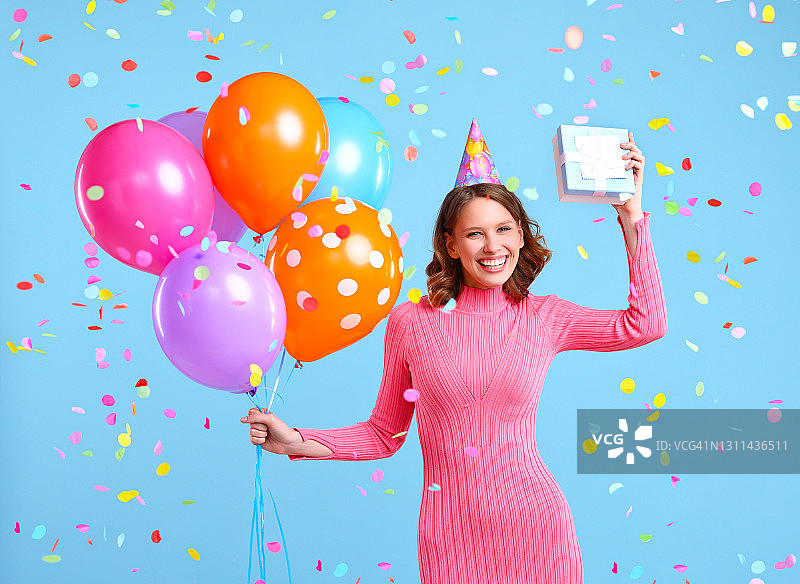 快乐的女子在五彩纸屑下拿着气球和礼物图片素材