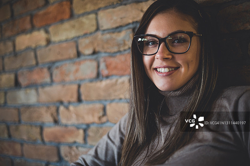 在咖啡馆休息的微笑眼镜女士靠墙而坐图片素材