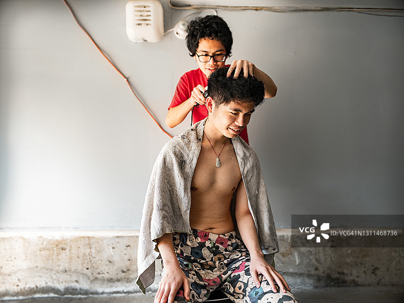 亚洲双胞胎青少年在家互相理发图片素材