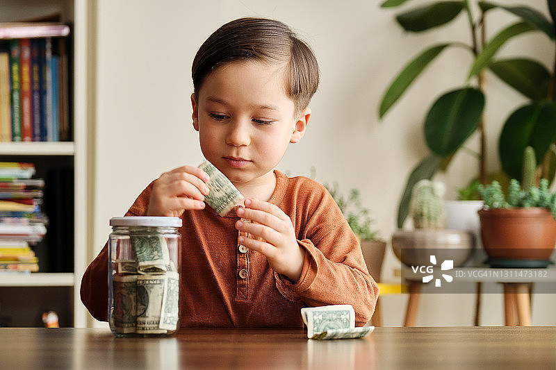 孩子在家中玻璃罐里存钱图片素材