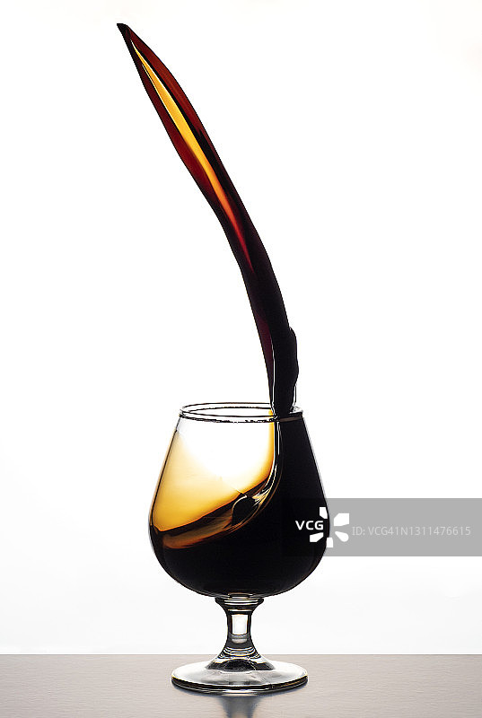 酒杯中飞溅的烈酒白色背景图片素材