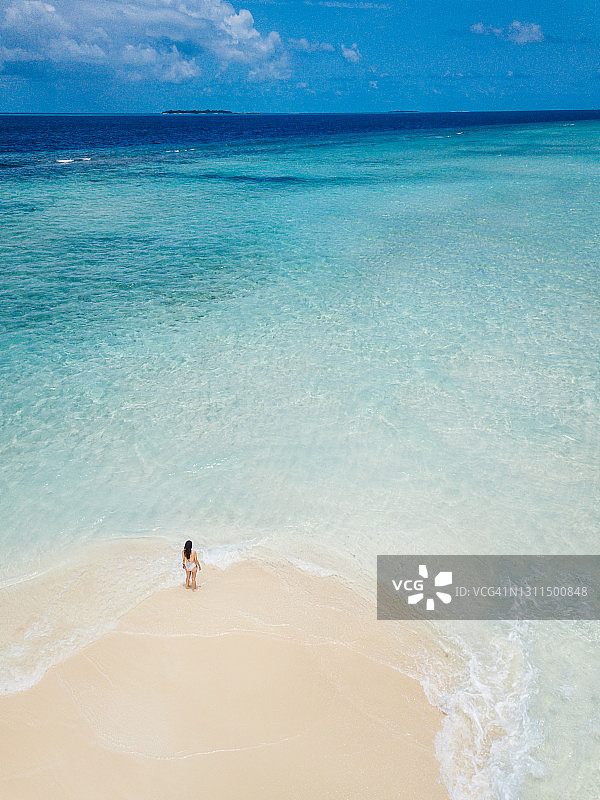 年轻女人站在马尔代夫绿松石水域的沙洲上图片素材