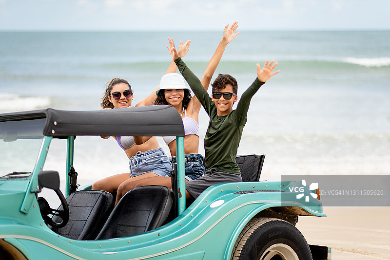 微笑的妈妈和孩子们坐在沙滩车的后座图片素材